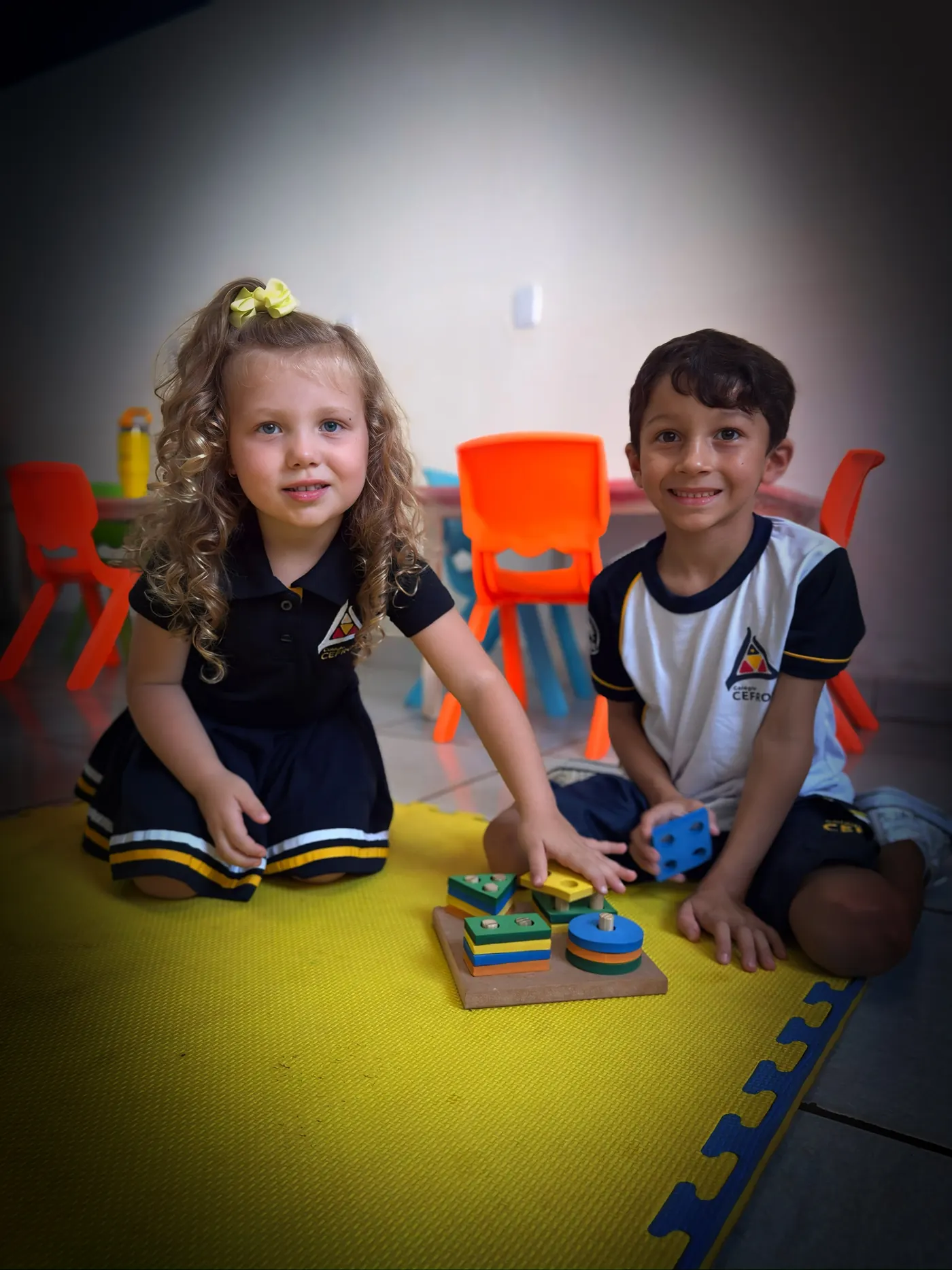 Duas crianças brincando com material pedagógico no tatame da Educação Infantil